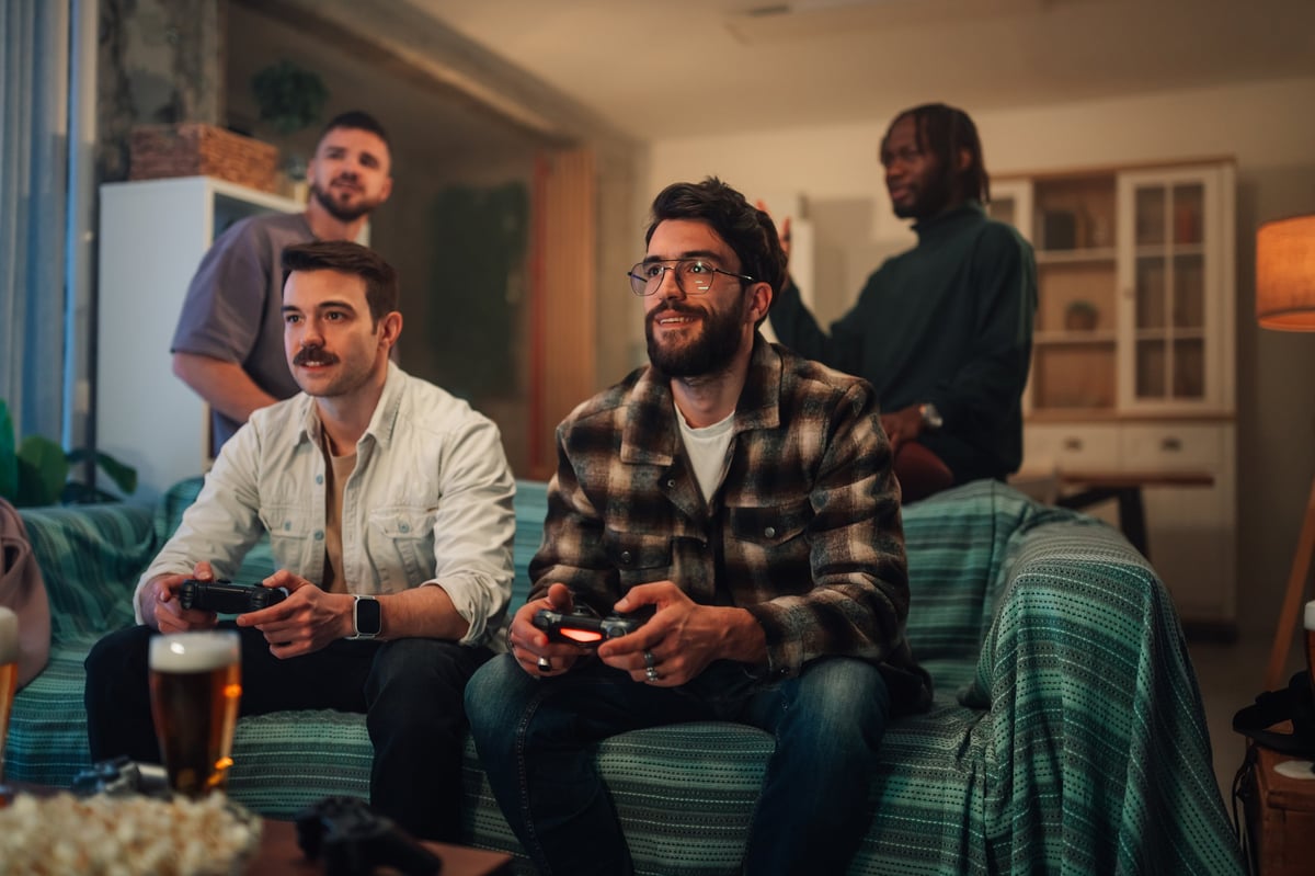 Group of young men in their twenties having a fun and lively video game tournament at home